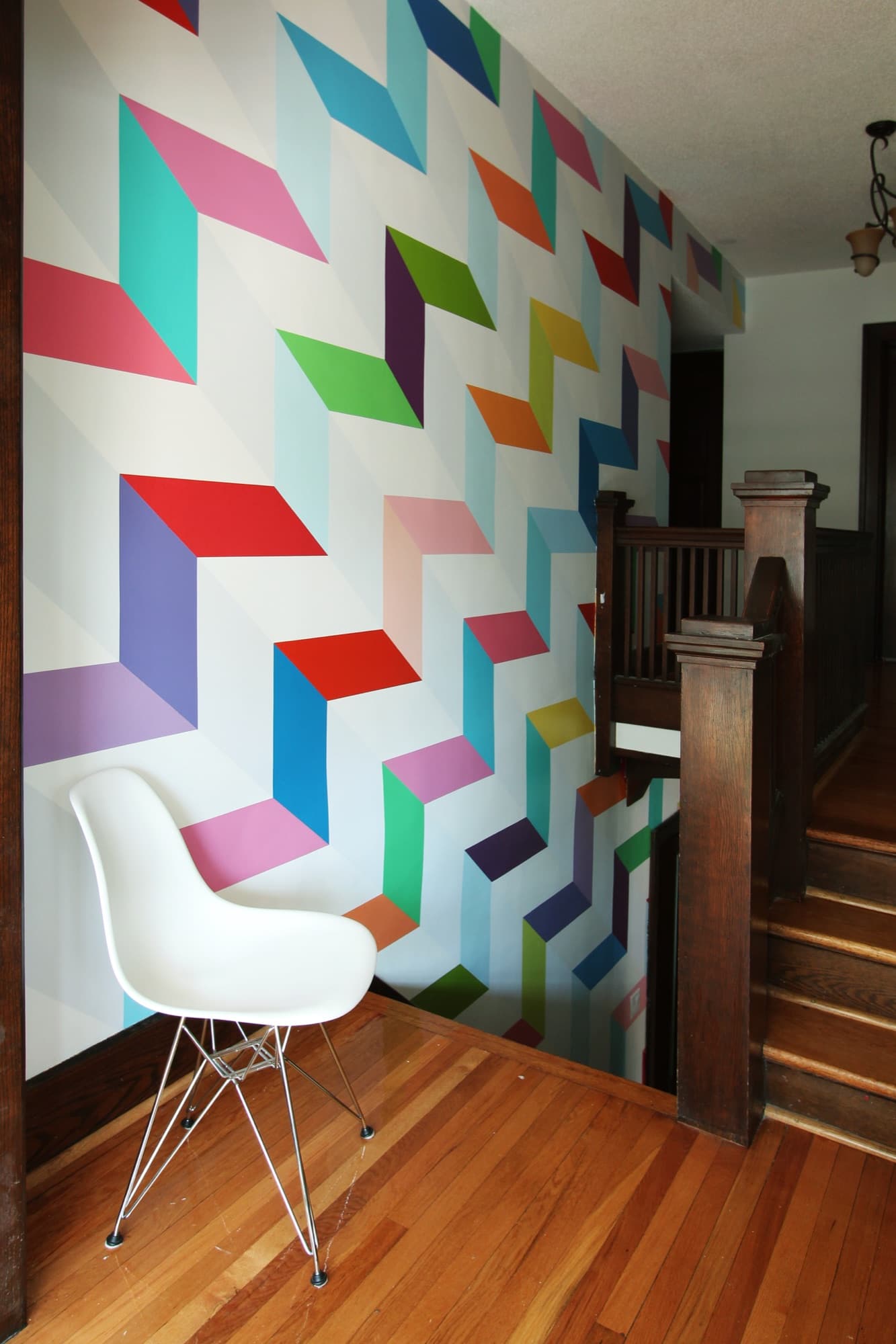 Multi-colour mural of stepped parallelograms cascading up a heritage staircase atrium wall.