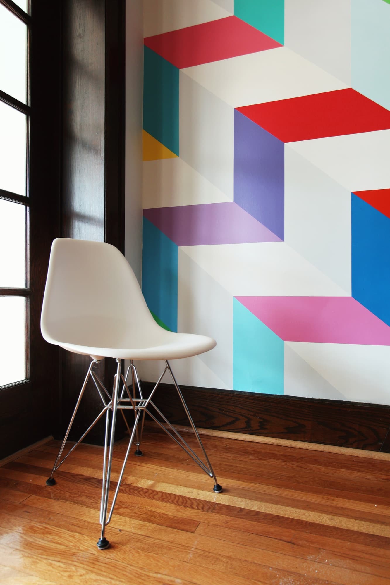 Chromatic Ascent — lower register of the wall, with an Eames chair at the base of the cascade.