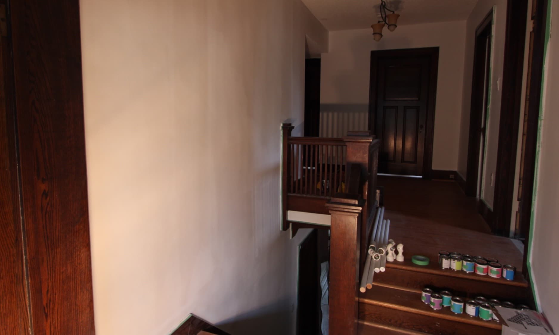 Chromatic Ascent — the prepared staircase wall, with the project's paint cans queued along the steps below.