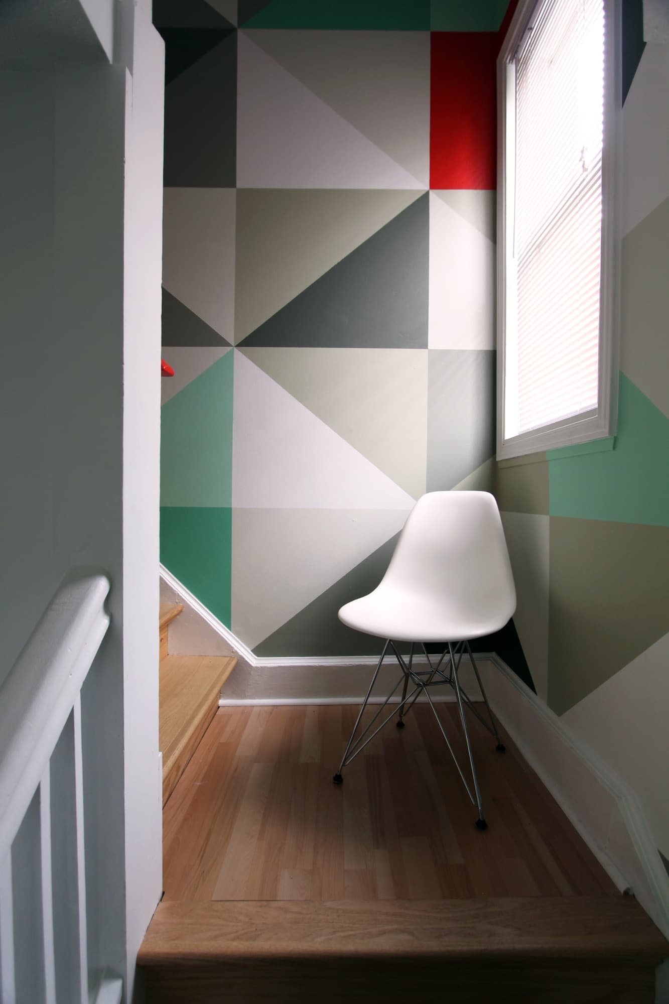 Mint & Vermillion — looking up from the lower landing toward the corner where the two walls meet.